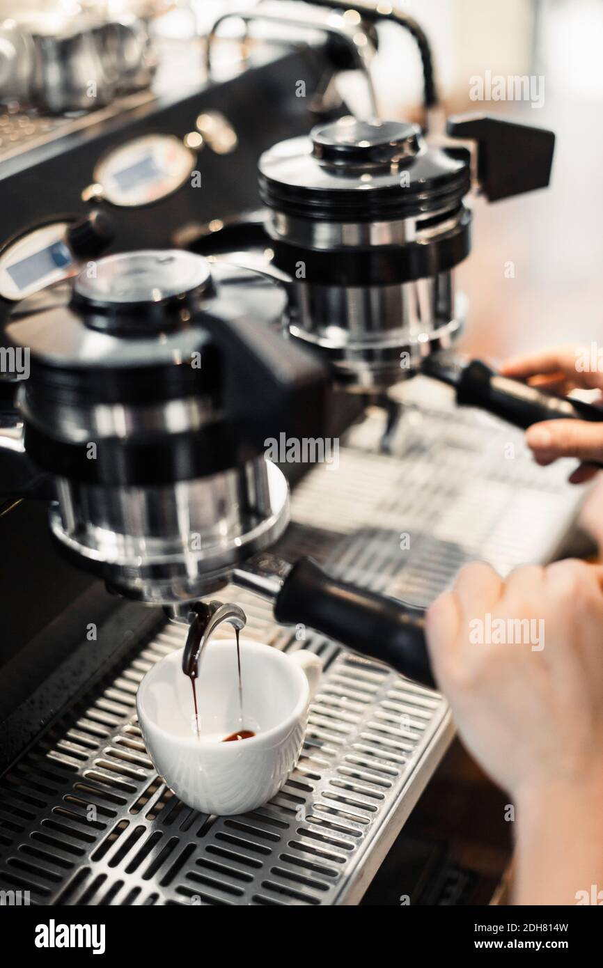 Zugeschnittenes Bild des Barista, der im Café eine Kaffeemaschine benutzt Stockfoto