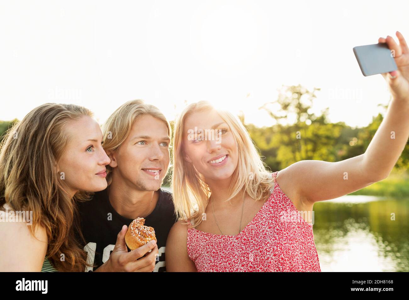 Glückliche Freunde, die Selfie beim Frühstück am See gegen Der Himmel ist klar Stockfoto