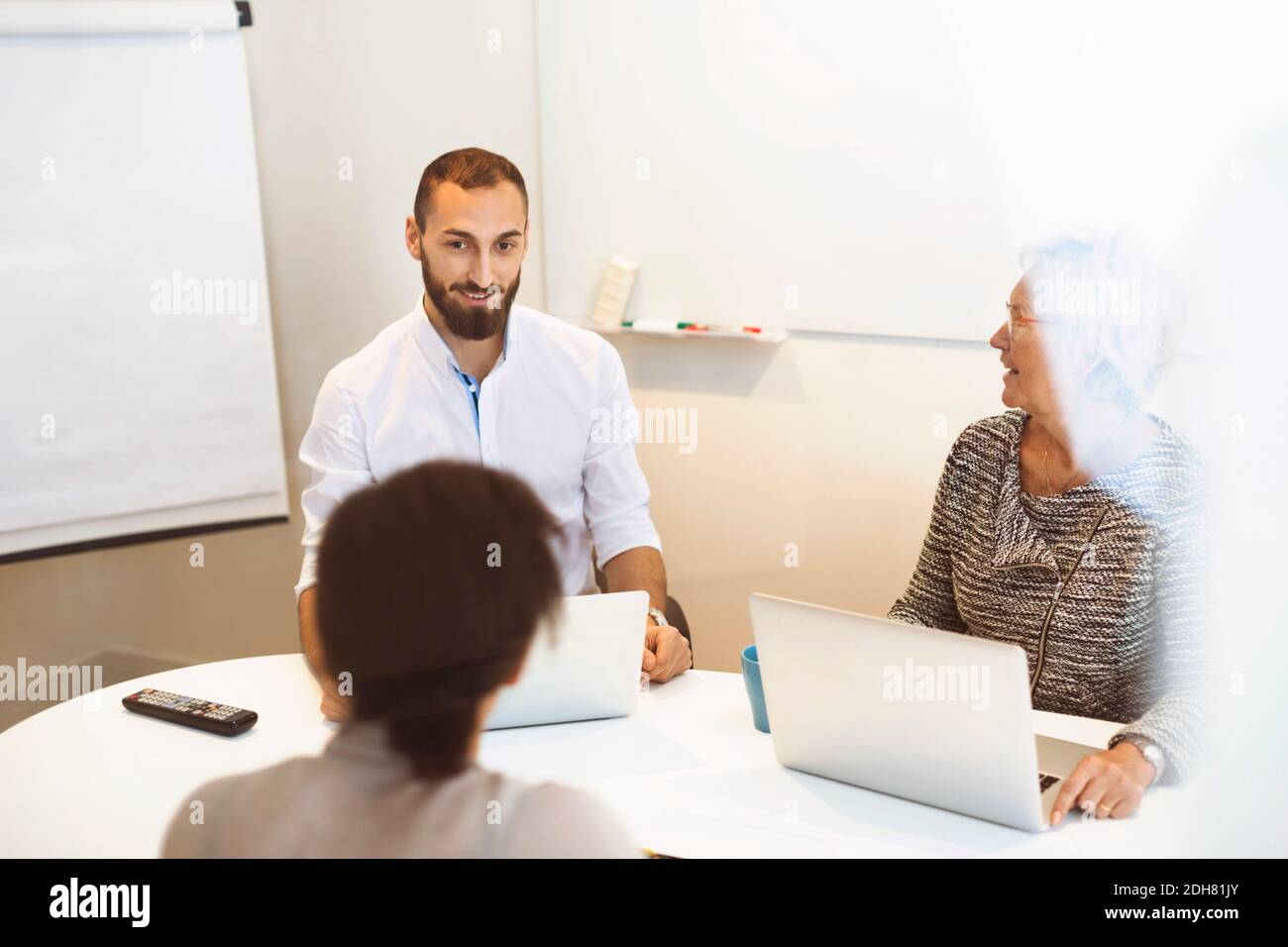 Geschäftsleute mit Laptops am Konferenztisch im Büro Stockfoto