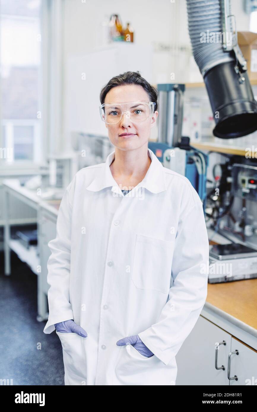 Porträt einer selbstbewussten Wissenschaftlerin, die mit den Händen in den Taschen steht Im Labor Stockfoto