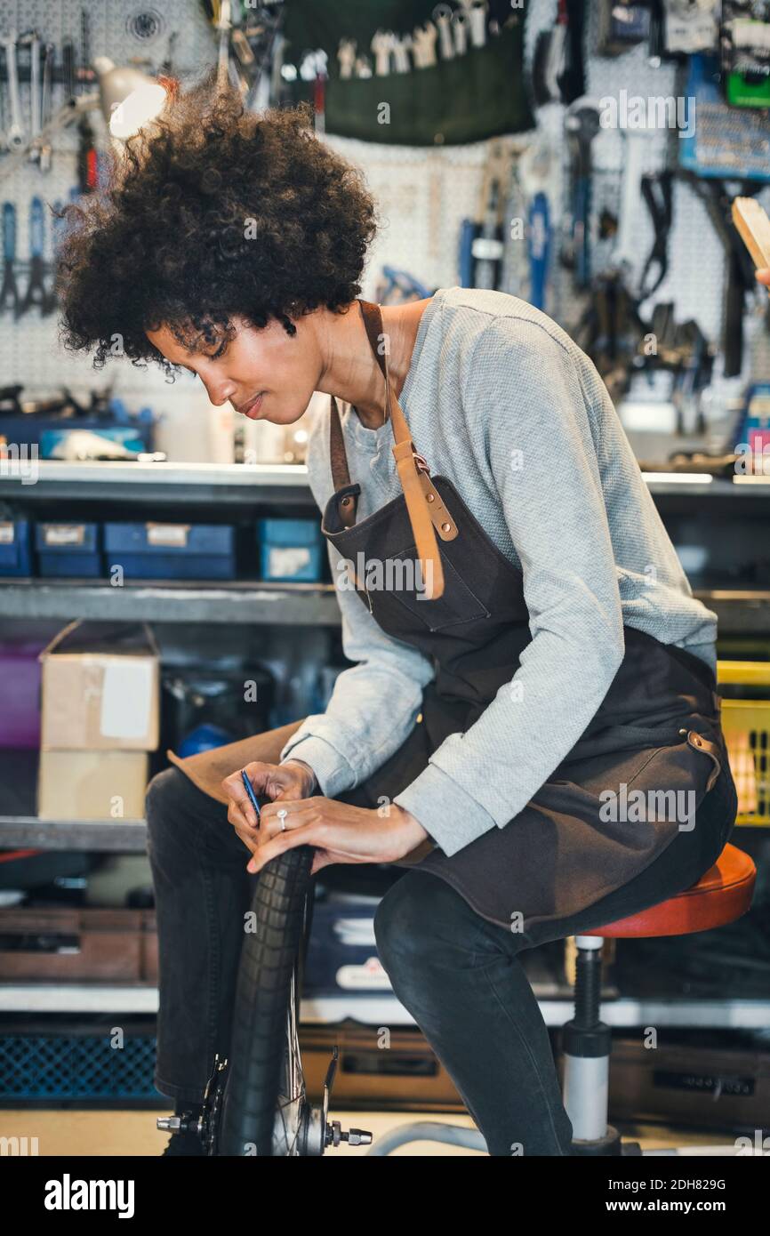 Mittlere Erwachsene weibliche Mechaniker Reparatur Fahrradreifen in der Werkstatt Stockfoto