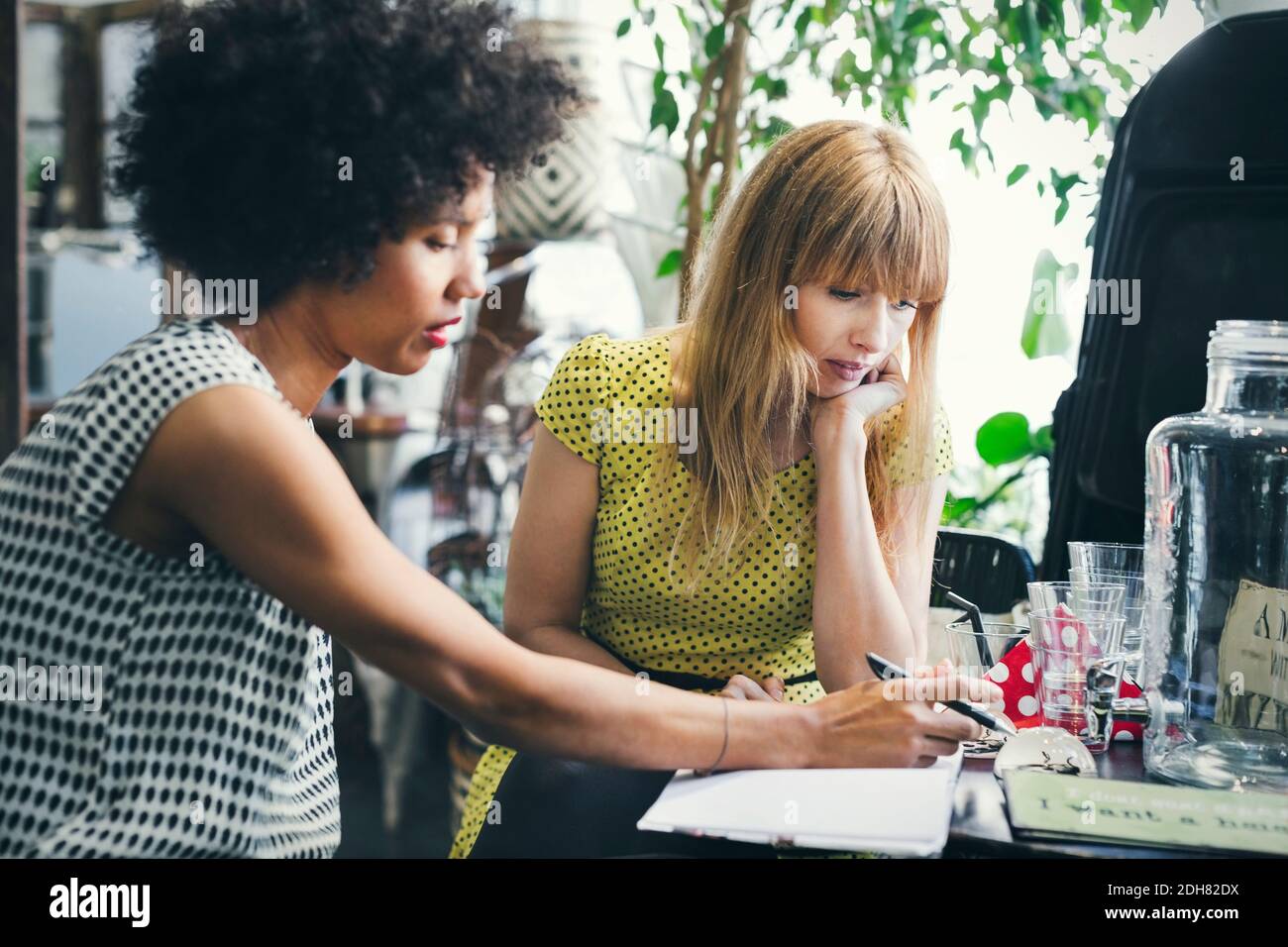 Mittlere Erwachsene Arbeiterinnen diskutieren in Innenarchitektur-Shop Stockfoto