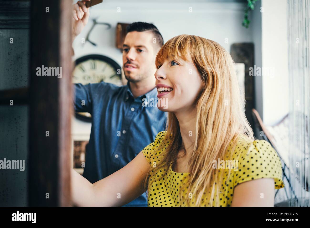 Lächelnde Frau mit mittlerem Erwachsenen, die mit einem Kollegen im Geschäft steht Stockfoto