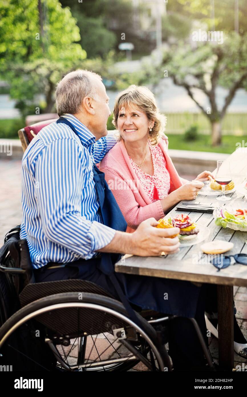 Glückliches reifes Paar, das sich beim Essen ansieht Im Hof Stockfoto