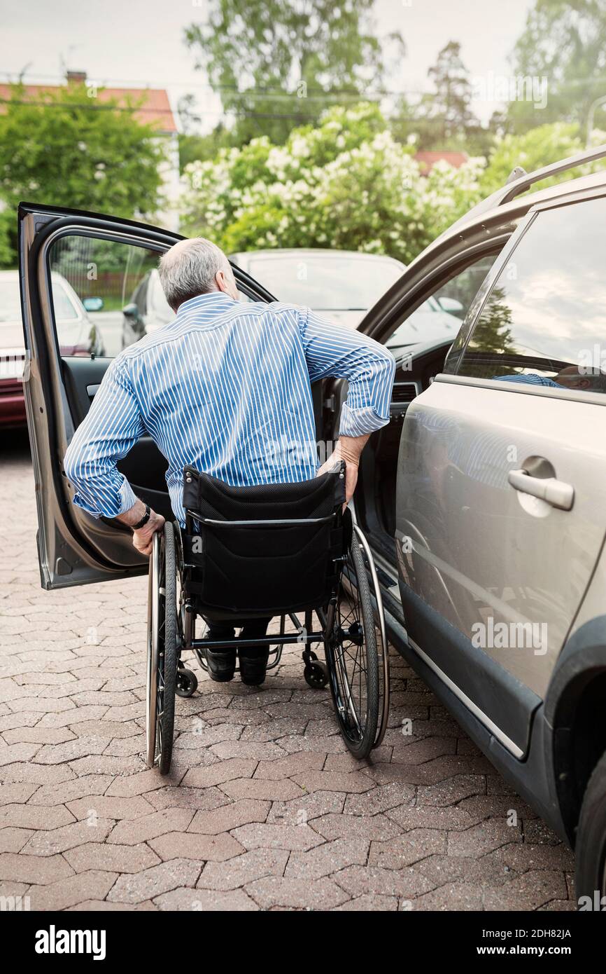 Rückansicht des Menschen im Rollstuhl vor dem Auto Stockfoto