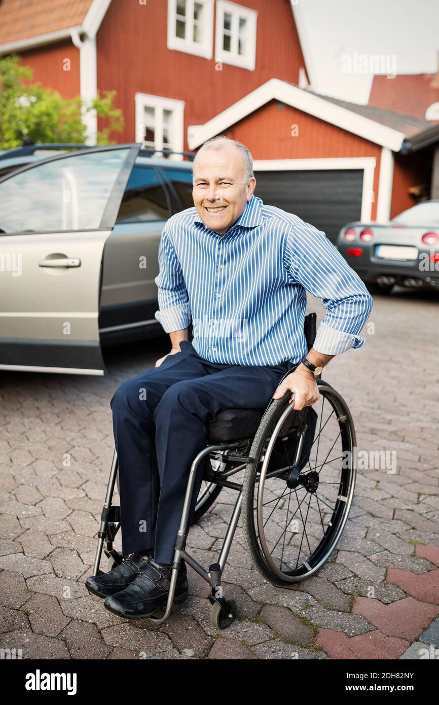 Porträt eines glücklichen Mannes, der im Rollstuhl auf der Straße sitzt Stockfoto