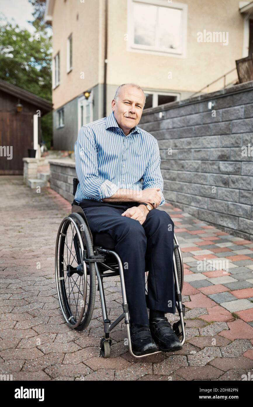 Porträt eines selbstbewussten Mannes, der im Rollstuhl auf der Straße sitzt Stockfoto
