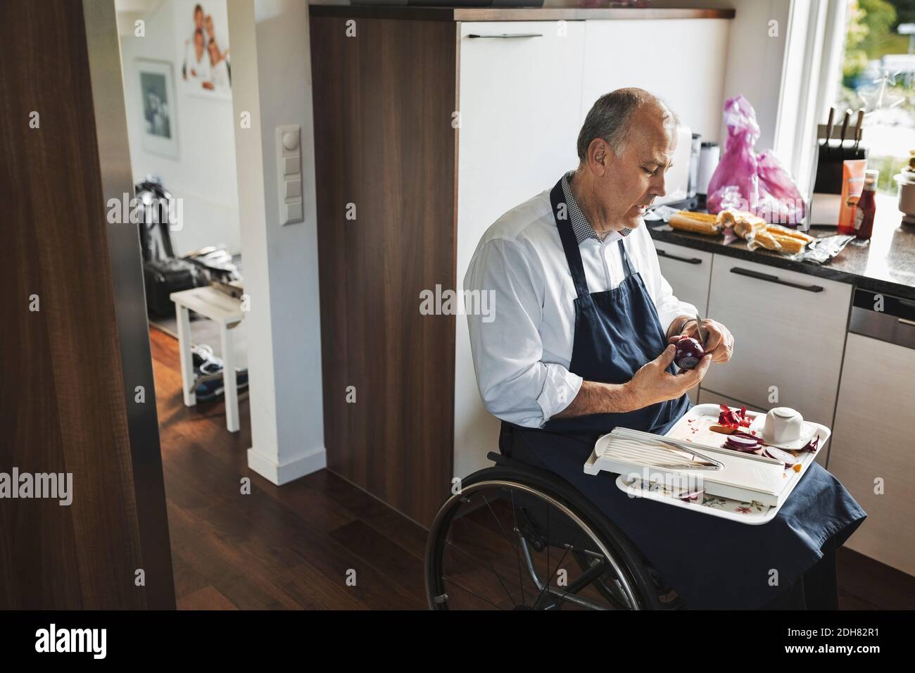 Behinderter Mann im Rollstuhl schneidet Zwiebel in der Küche Stockfoto