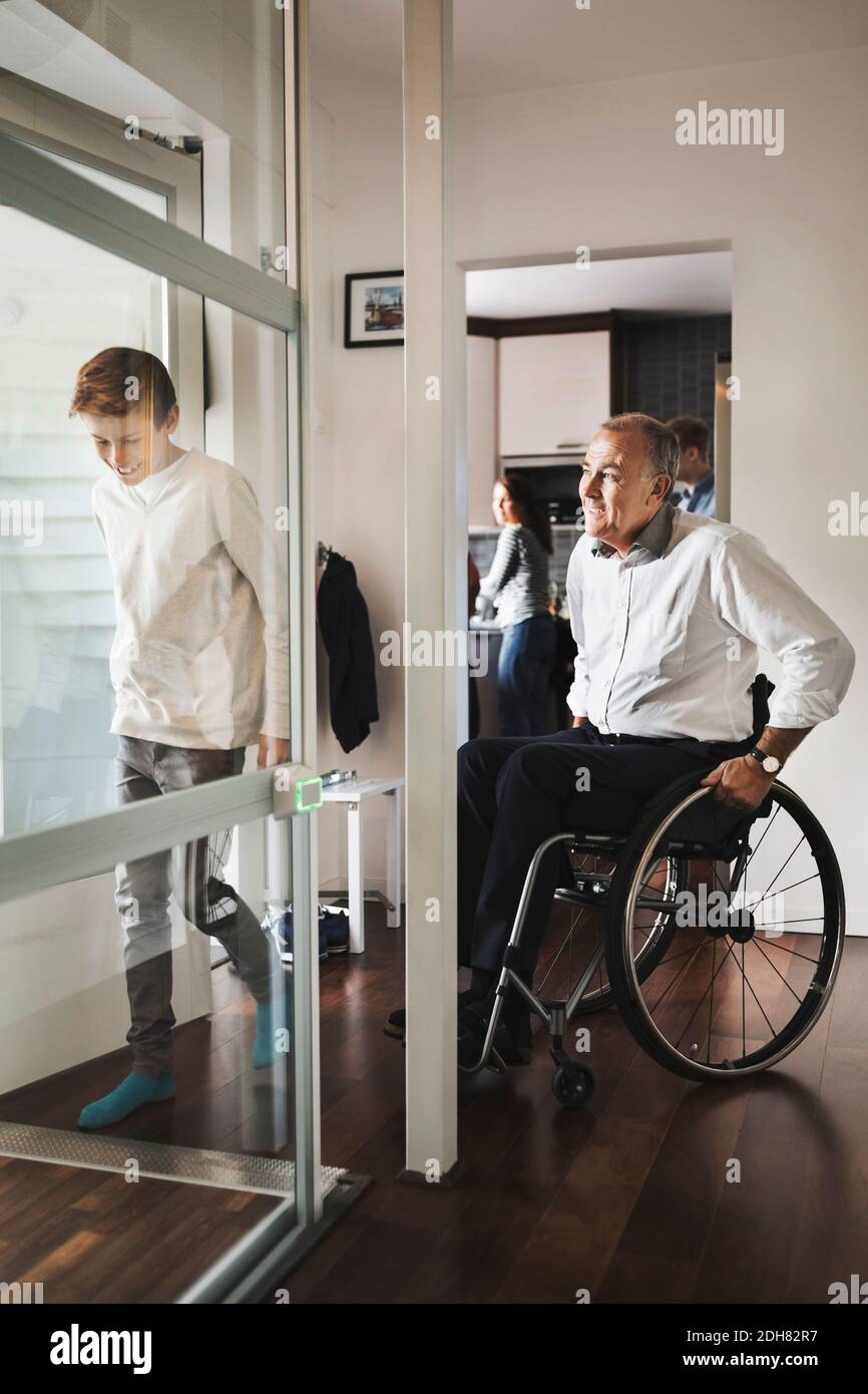 Sohn und Vater betreten Rollstuhllift zu Hause Stockfoto