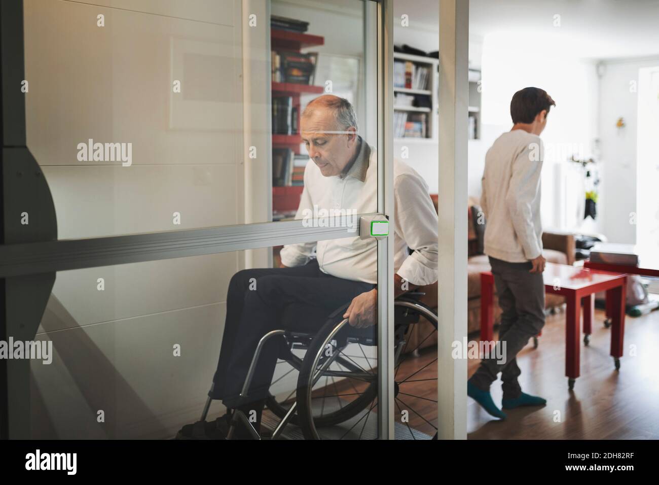 Behinderter Mann im Rollstuhl, der zu Hause aus dem Lift kommt Stockfoto