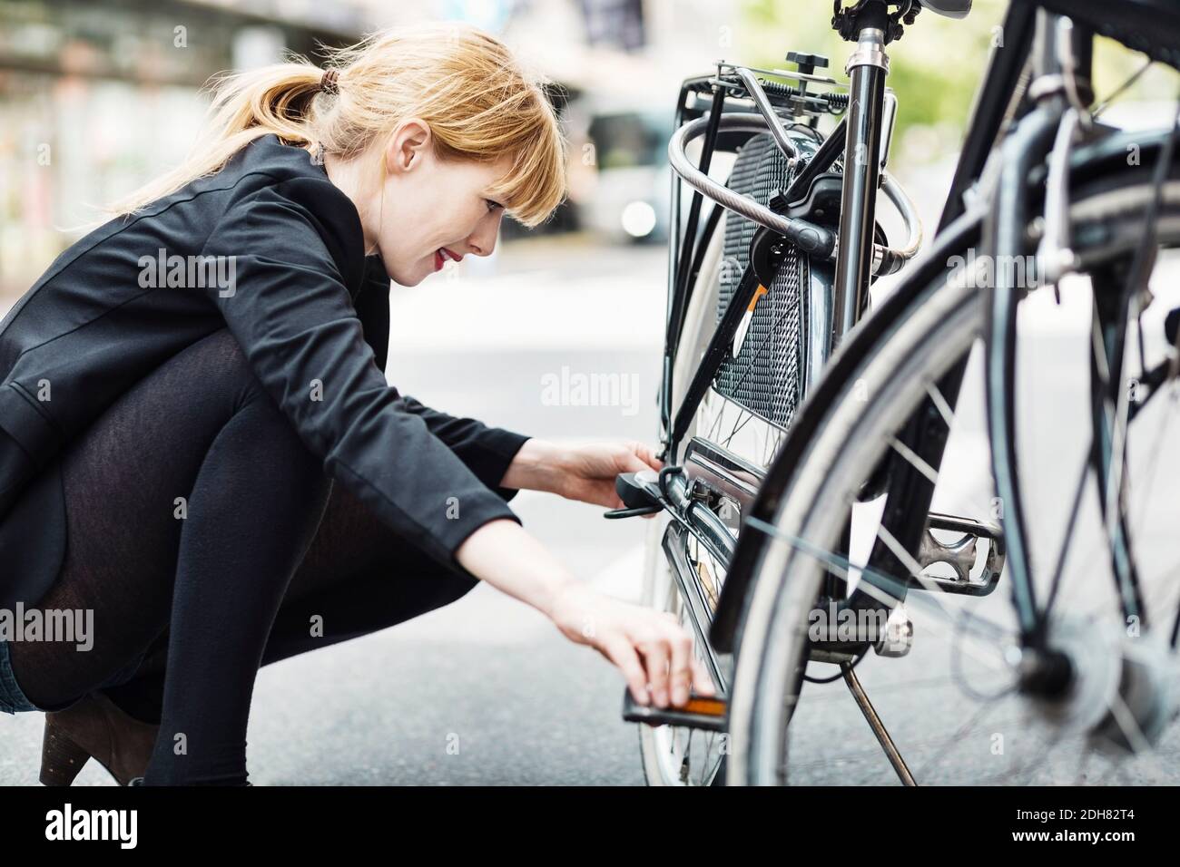 Seitenansicht der Geschäftsfrau Reparatur Fahrrad auf der Straße Stockfoto