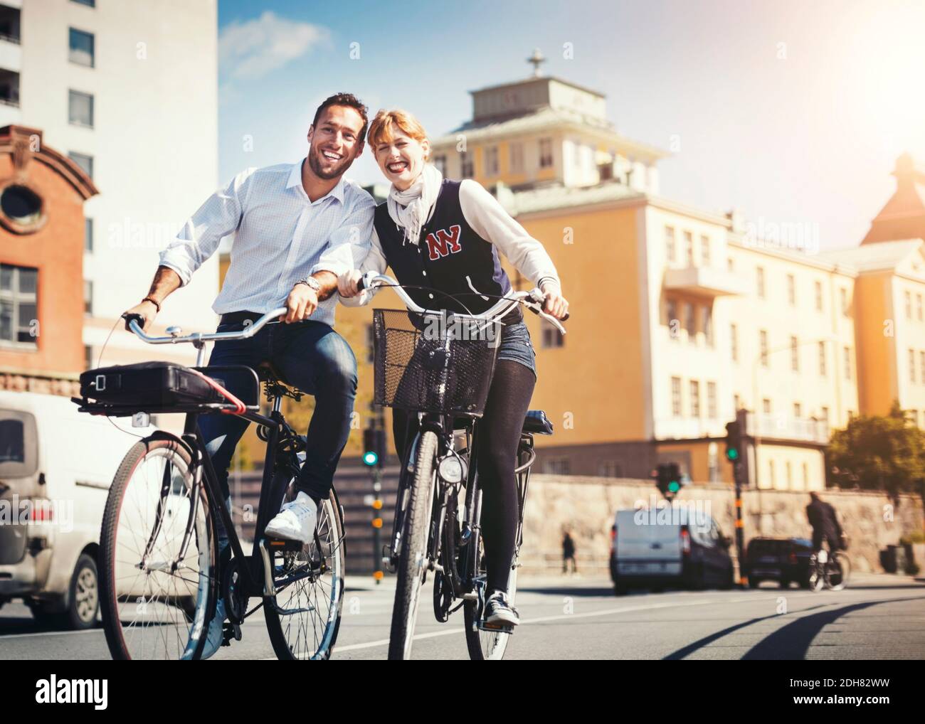 Glückliche Geschäftsleute, die auf der Stadtstraße Fahrrad fahren Stockfoto