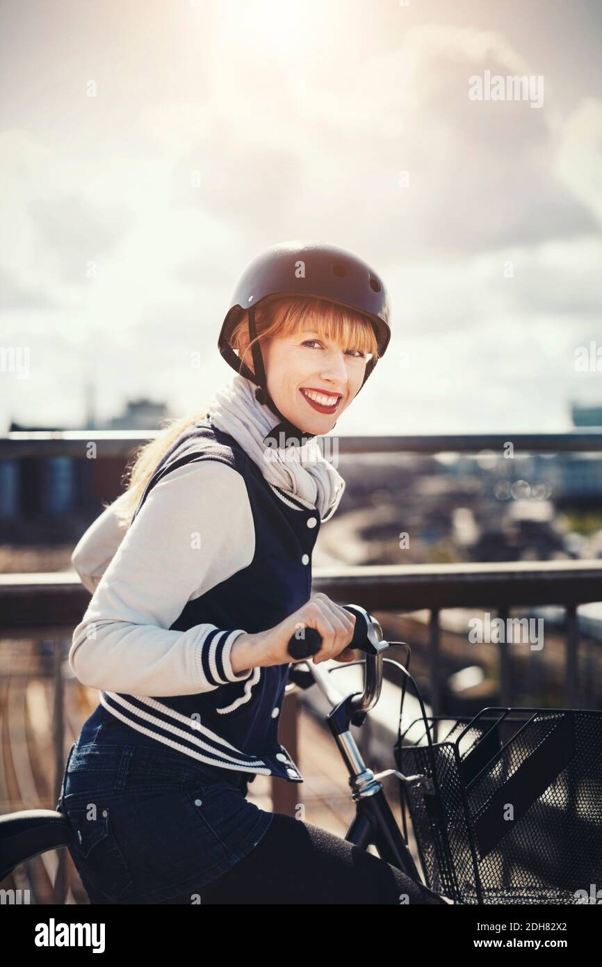 Seitenansicht Porträt einer glücklichen Geschäftsfrau stehend mit Fahrrad auf Brücke Stockfoto