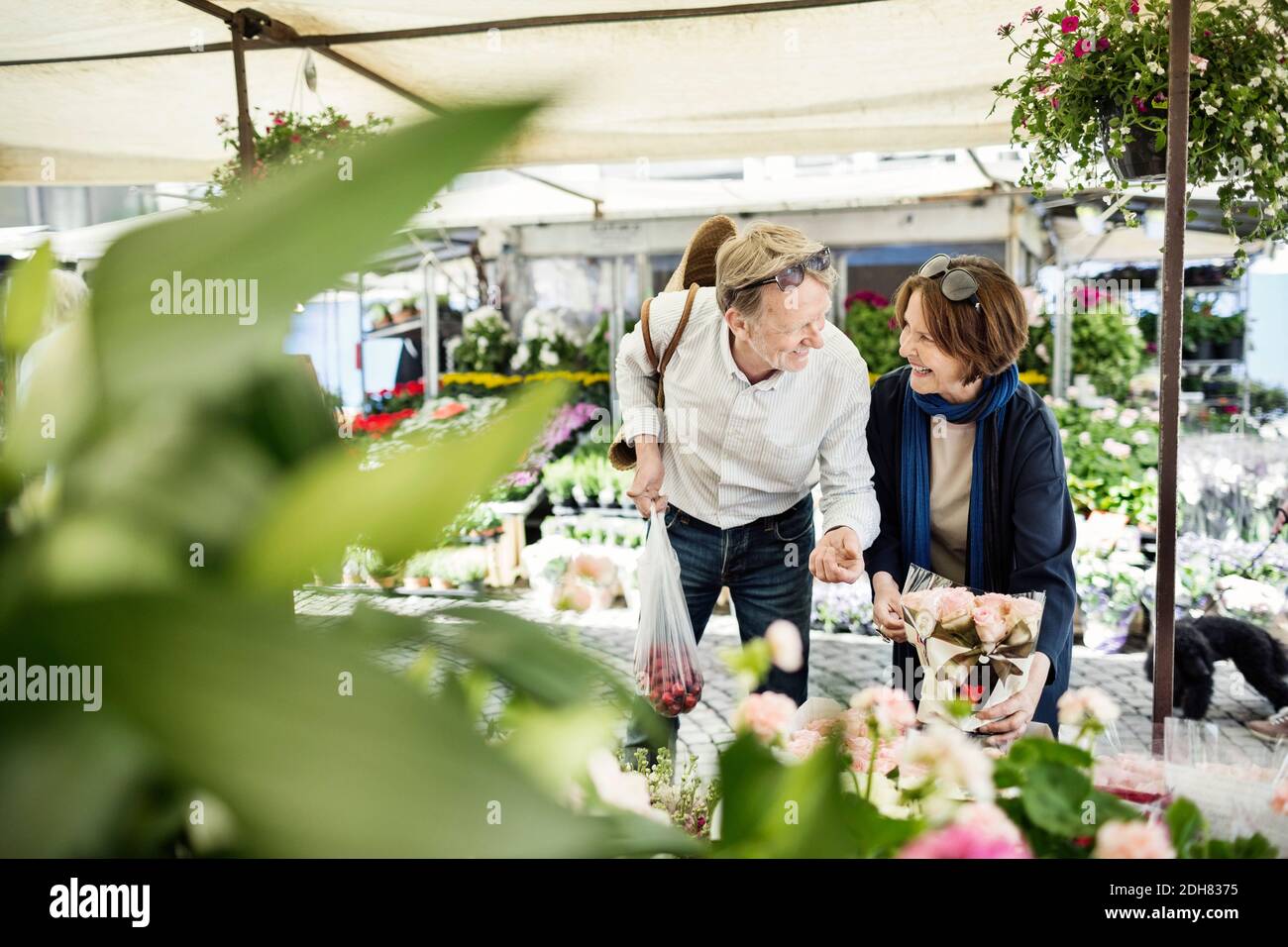 Glückliches Seniorenpaar, das beim Kauf von Blumen auf dem Markt spricht Stockfoto