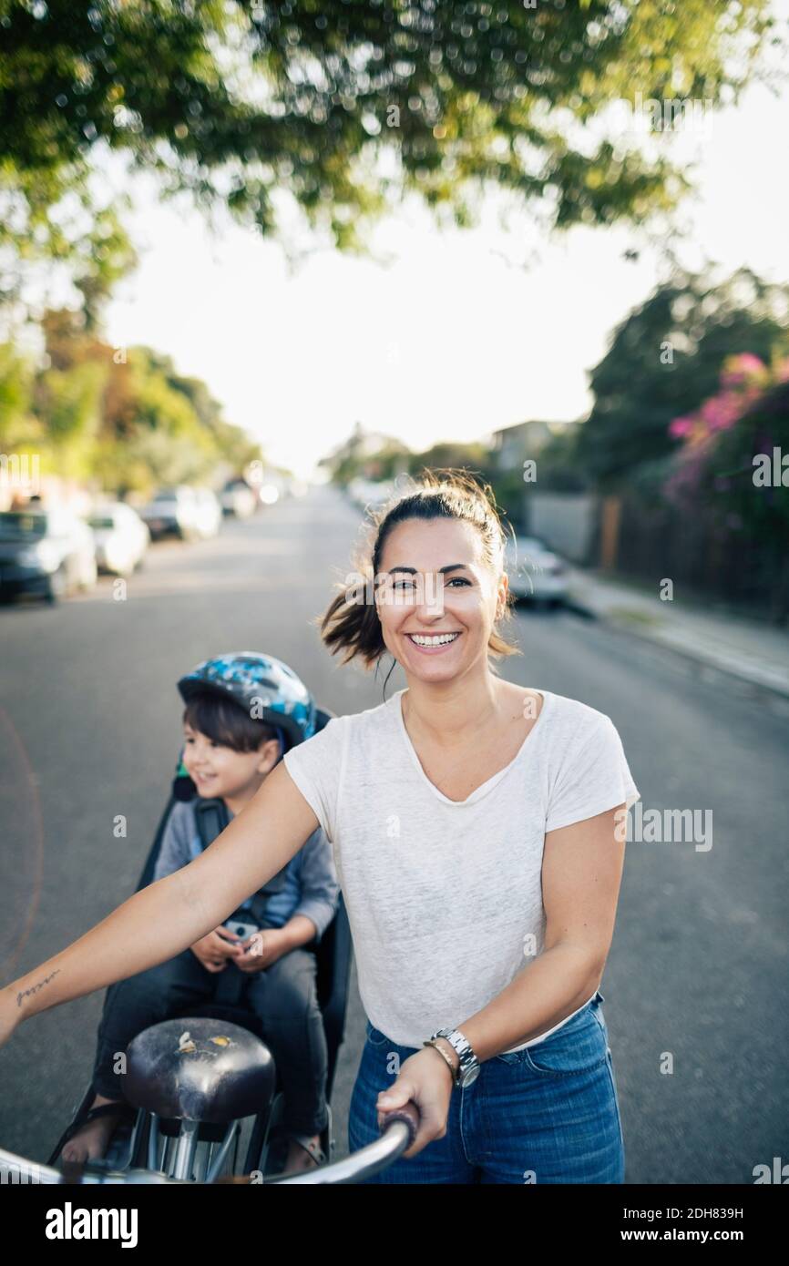 Porträt einer glücklichen Frau mit Fahrrad und Sohn sitzend Rücksitz Stockfoto