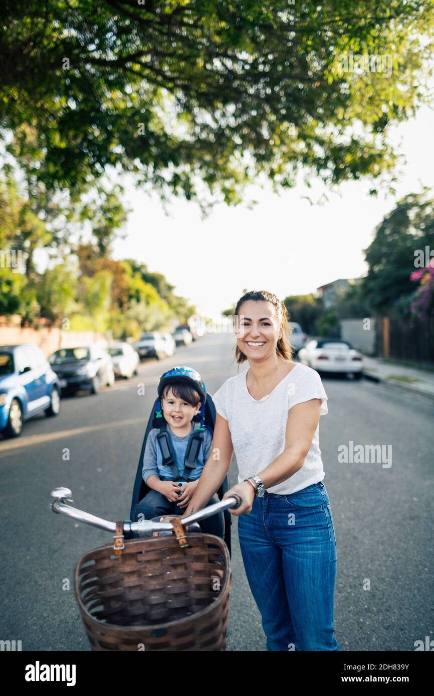 Porträt von glücklicher Mutter und Sohn mit Fahrrad auf der Straße Stockfoto