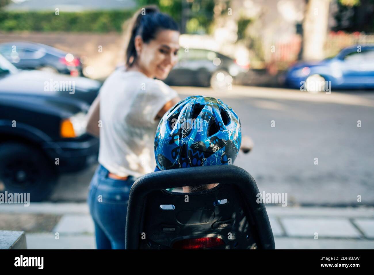 Lächelnde Frau schaut Sohn auf dem Fahrrad auf der Straße sitzen Stockfoto
