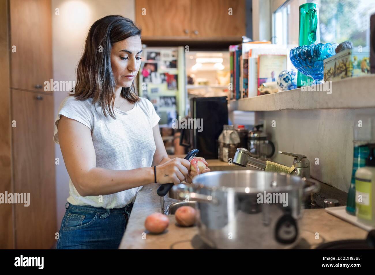 Frau schälte Kartoffeln an der Küchentheke Stockfoto
