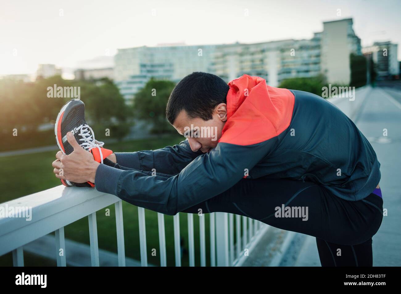 Mann streckt Bein auf Geländer am Bürgersteig Stockfoto