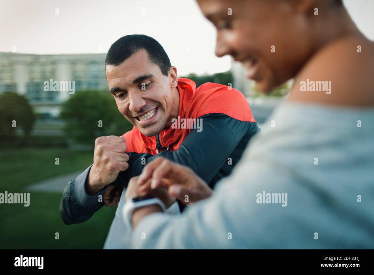 Mann feiert den Sieg, während Frau Zeit auf Smart Watch überprüfen Stockfoto