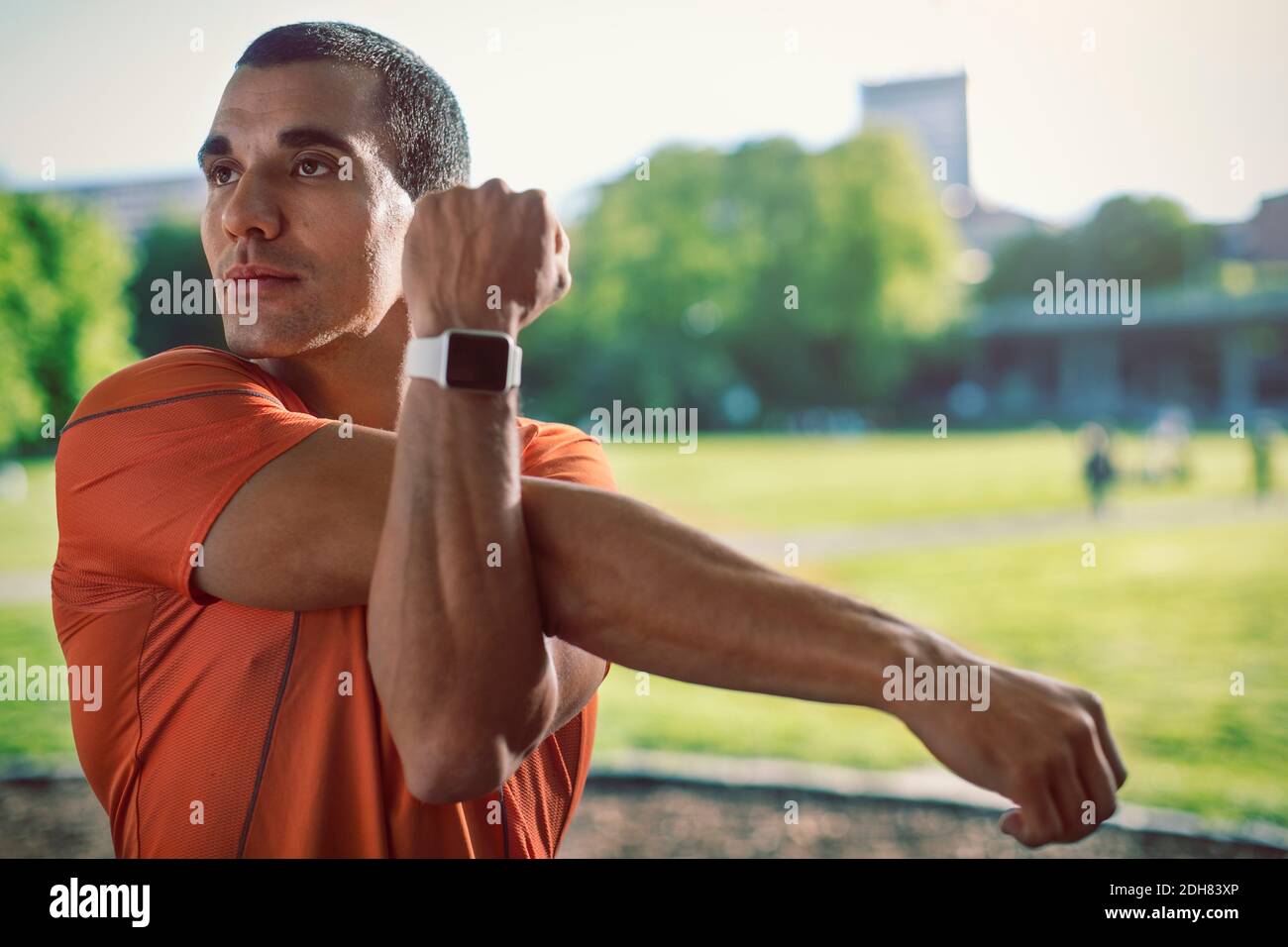 Mann mit Armbanduhr Stretching Arm im Park Stockfoto