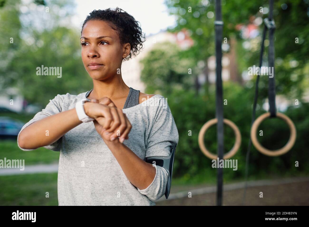 Frau mit Smart Watch beim Blick weg in den Park Stockfoto
