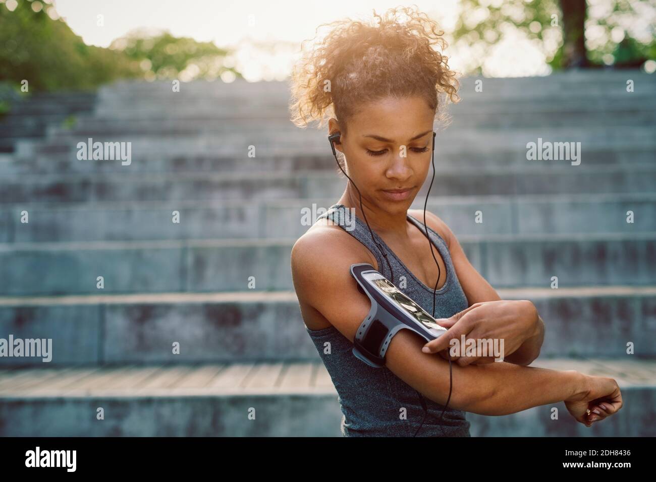 Frau mit Smartphone Armband während des Trainings Stockfoto