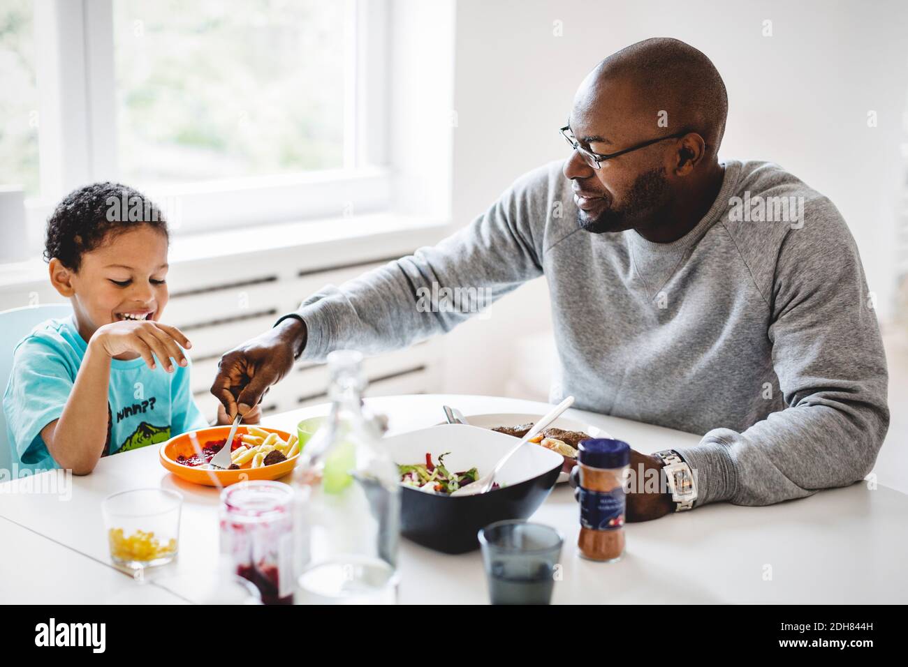 Vater, der mit dem Sohn am Esstisch im Haus gegessen hat Stockfoto