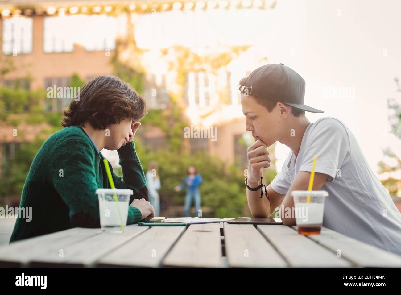 Seitenansicht von Teenagerjungen, die am Tisch im Freien studieren Stockfoto