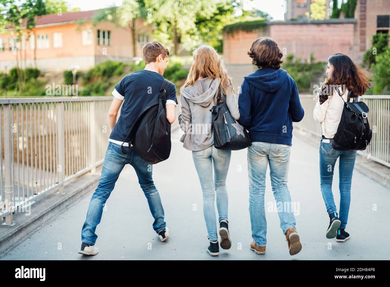 Rückansicht von Teenagern, die auf der Brücke in der Stadt spazieren Stockfoto