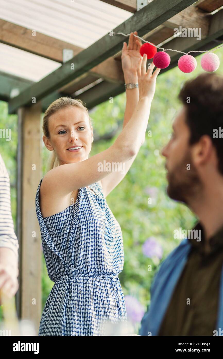 Lächelnde Frau, die den Mann ansieht, während sie die Blockhütte dekorieren Sommerfest Stockfoto