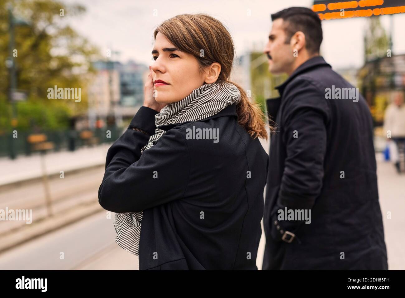 Seitenansicht der weiblichen und männlichen Passagiere, die auf die Straßenbahn warten Auf der Plattform Stockfoto