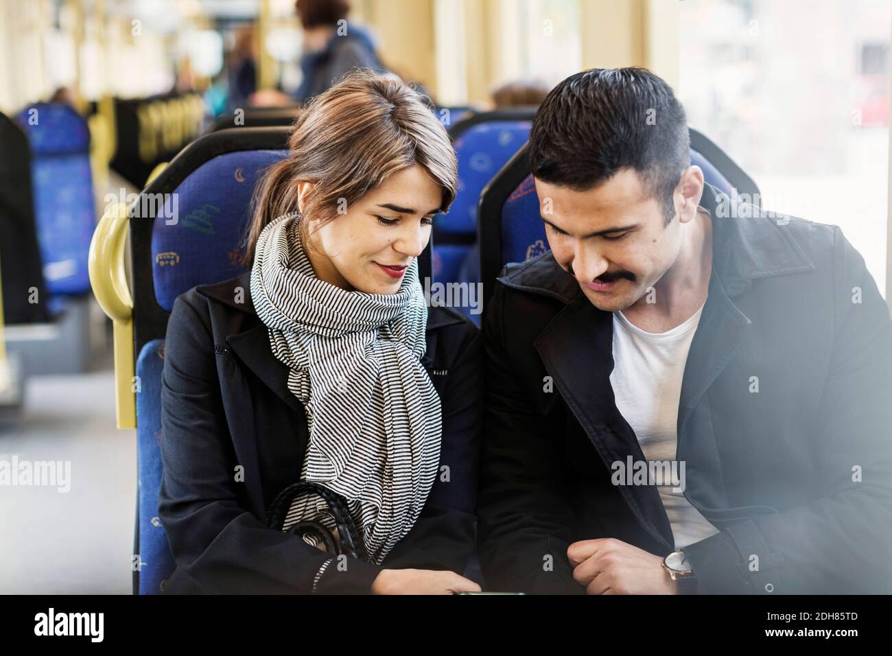Lächelndes Paar, das in der Straßenbahn herunterschaute Stockfoto