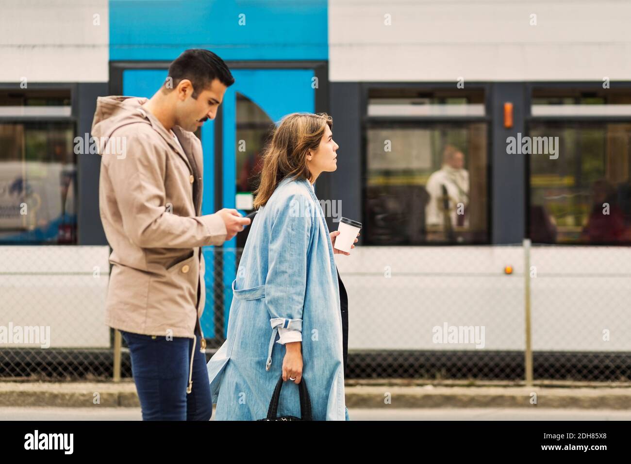 Seitenansicht des jungen Mannes und der Frau, die in der Straßenbahn stehen Station Stockfoto