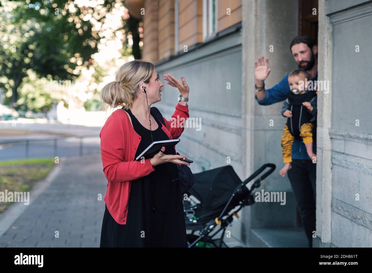 Mittlere Erwachsene Mutter winkt Familie während der Abreise zur Arbeit Stockfoto