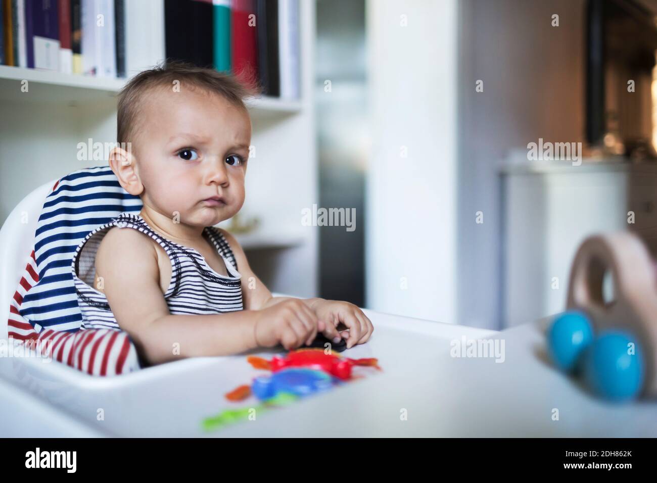 Nachdenklich Baby Junge sitzt im Hochstuhl zu Hause Stockfoto