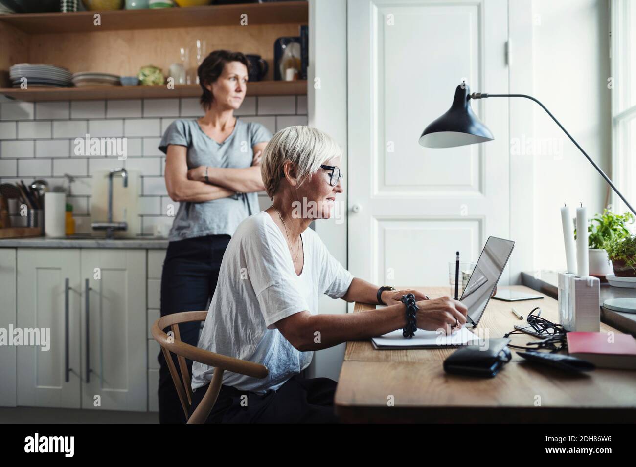 Industriedesigner mit Laptop am Tisch und Kollege im Tisch Küche Stockfoto