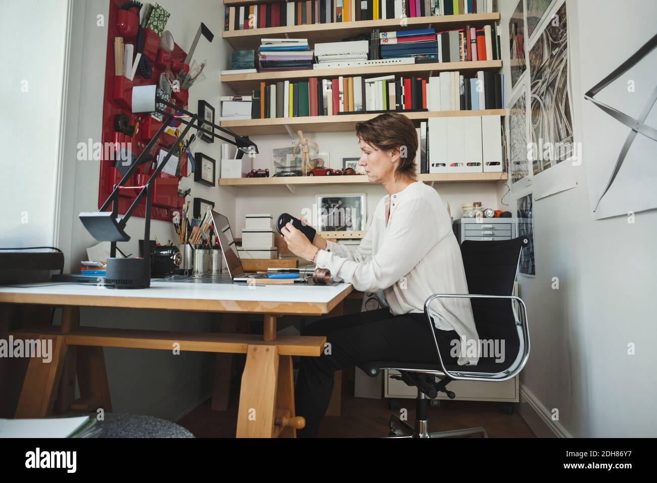 Seitenansicht des Industriedesigners, der das Produkt im Home Office analysiert Stockfoto