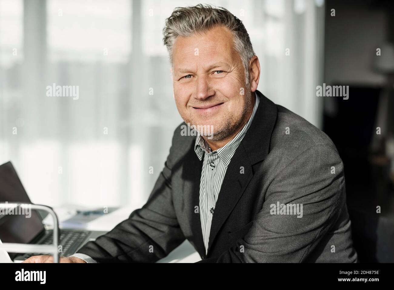 Porträt eines lächelnden Geschäftsmannes, der im Büro sitzt Stockfoto
