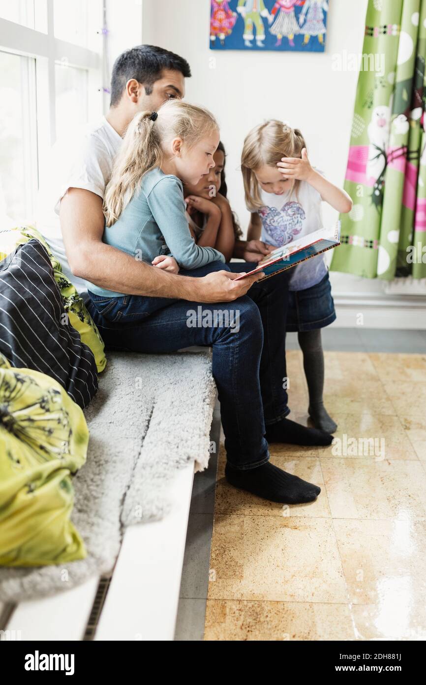 Lehrer und Mädchen lesen Geschichte Buch in der Tagesstätte Stockfoto