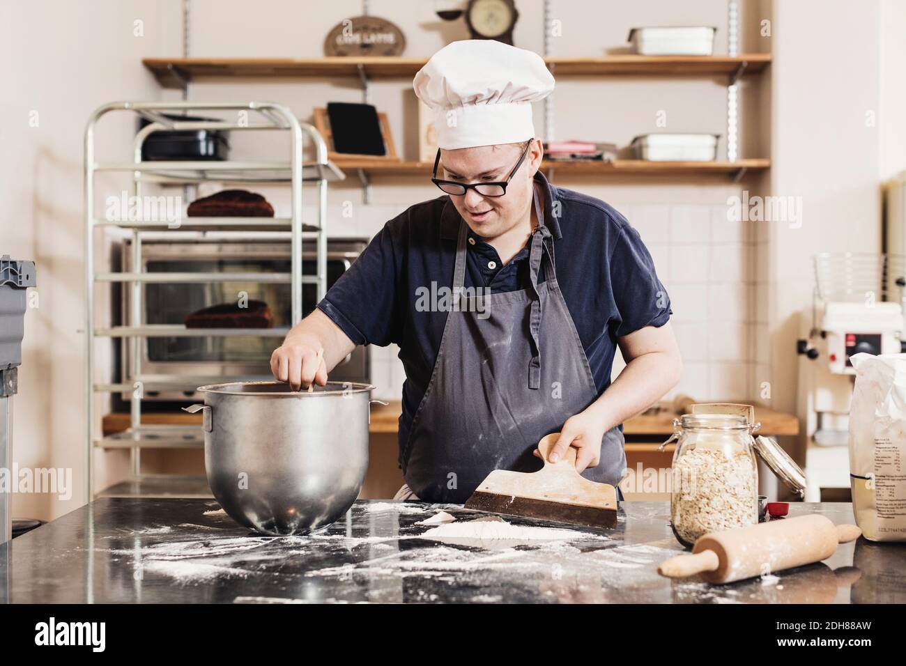 Junger Mann, der Teig an der Küchentheke macht Stockfoto