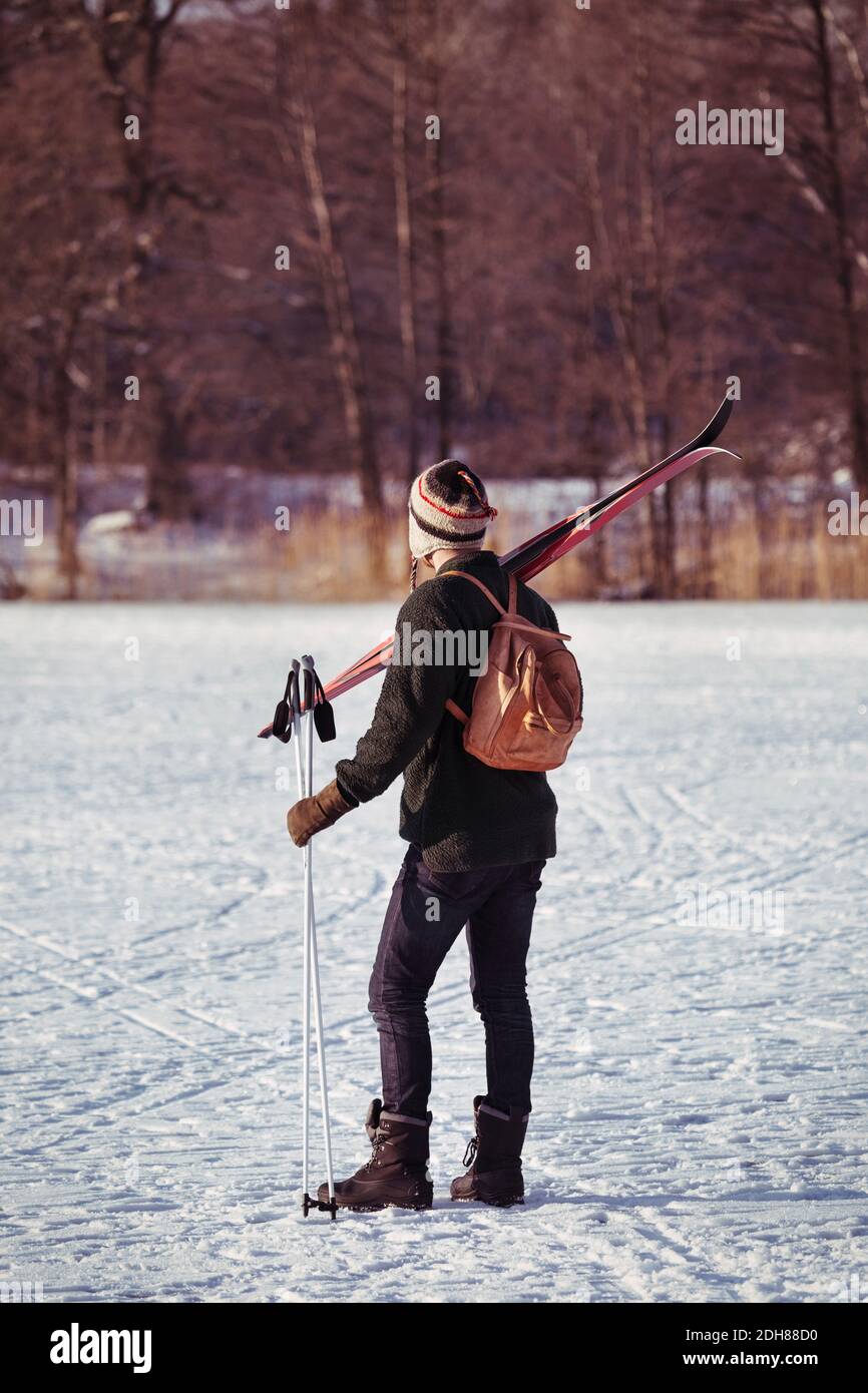 Rückansicht des männlichen Wanderers, der die Skiausrüstung auf dem Feld trägt Stockfoto