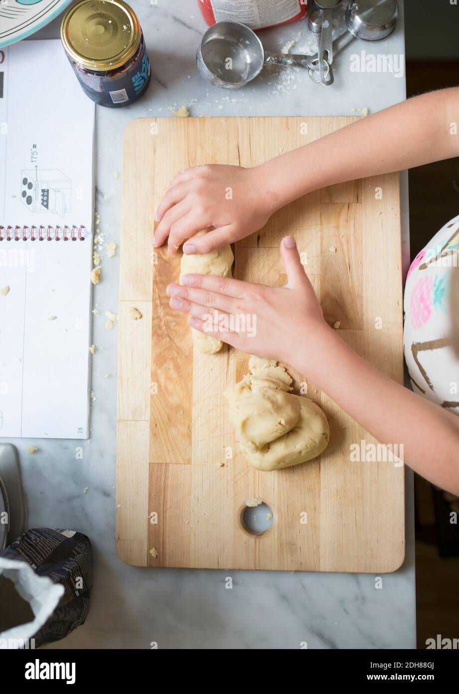 Zugeschnittenes Bild von Mädchen machen Teig auf Schneidebrett bei Küche Stockfoto