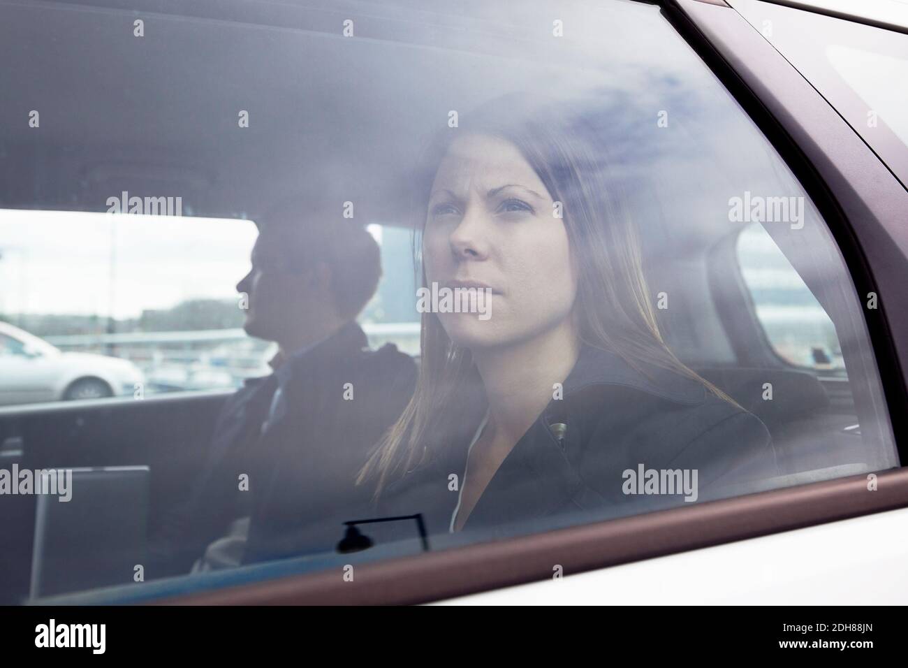 Geschäftsfrau, die auf dem Rücksitz des Autos sitzt und herausschaut Des Fensters Stockfoto