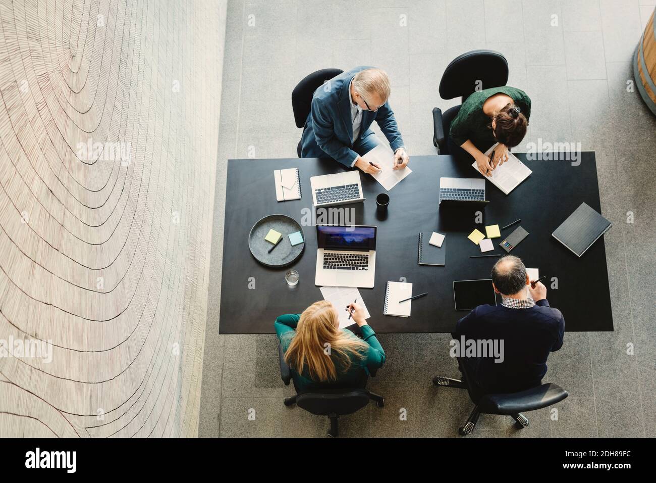 Blick aus der Perspektive der multiethnischen Geschäftsleute, die am Tisch arbeiten Im kreativen Büro Stockfoto