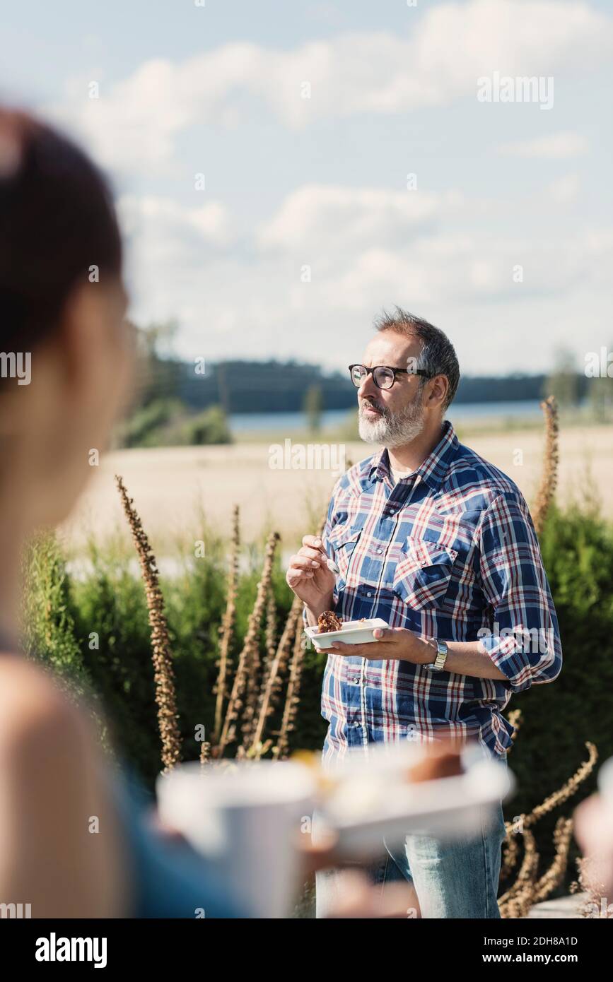 Reifer Mann Essen mit Freunden im Hinterhof auf Sonniger Tag Stockfoto