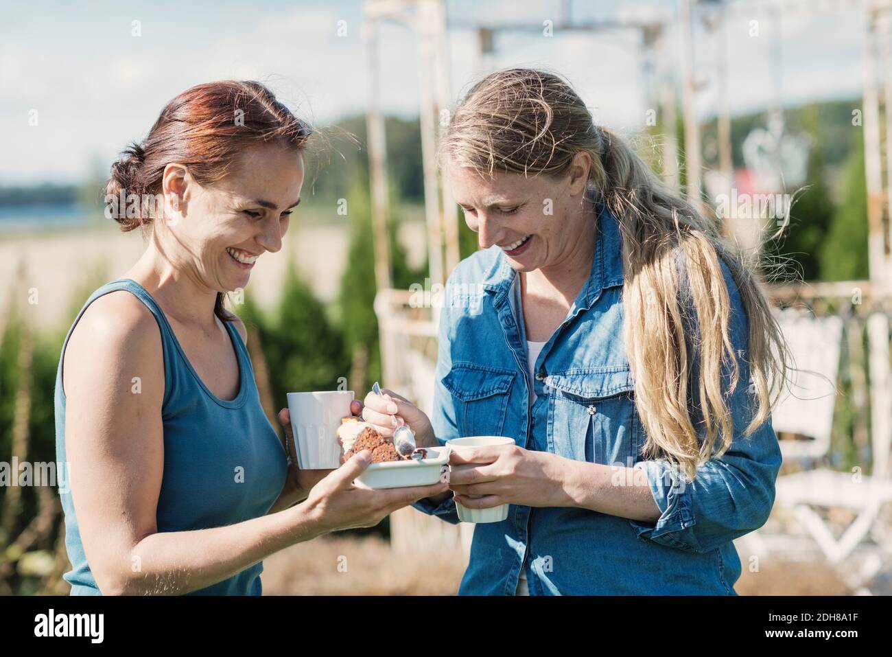 Fröhliche Freundinnen genießen Essen mit Kaffee im Hinterhof Stockfoto