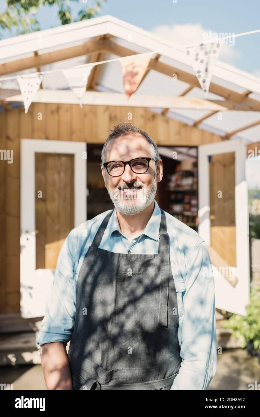 Portrait von glücklichen reifen Ladenbesitzer, der gegen den Laden steht Stockfoto