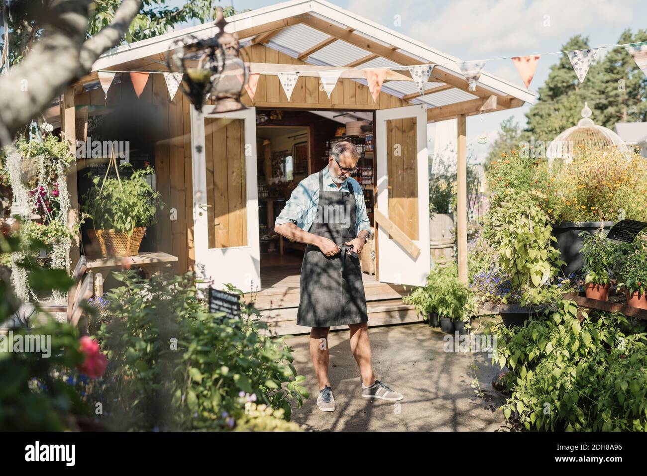 Reifer Ladenbesitzer, der auf dem Gehweg gegen den Laden steht Stockfoto