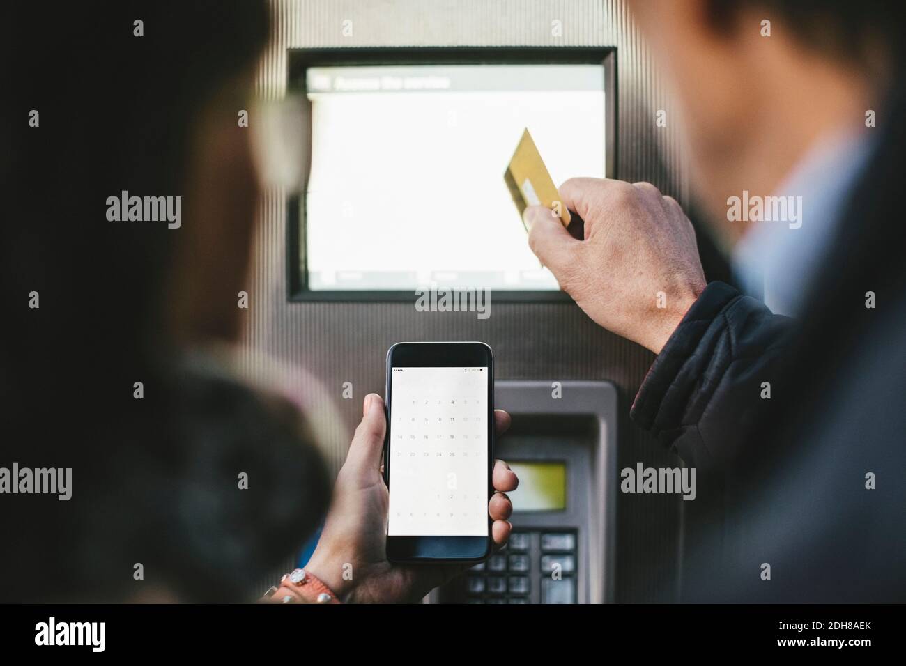 Ältere Paare, die die Zahlung per Kreditkarte und Mobiltelefon vornehmen An der Fahrradverleihstation Stockfoto